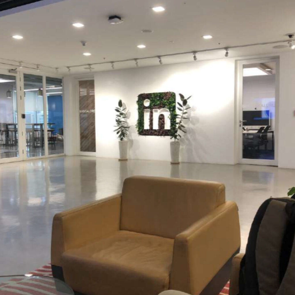 Office lobby with tan leather sofas, glass walls, and potted plants.",