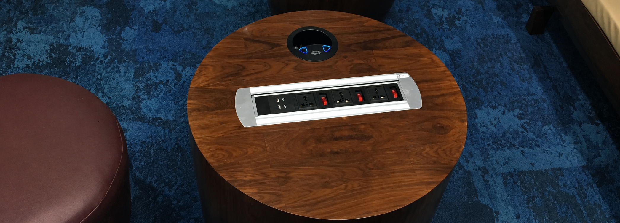 Round wooden coffee table with a built-in electrical outlet strip and a circular cable/cord access hole at the center.